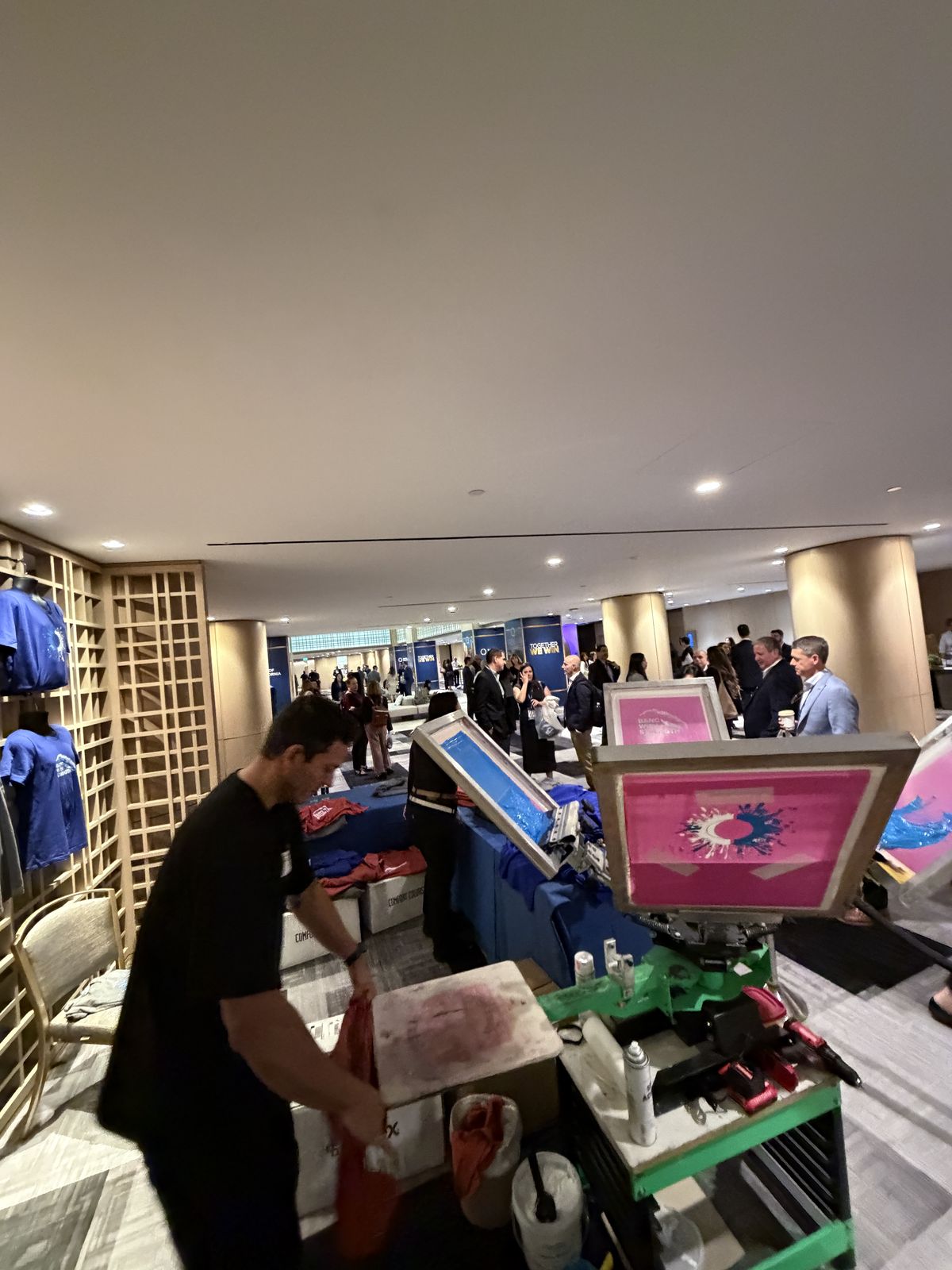 Crowd gathered around a running screen-printing press at an event